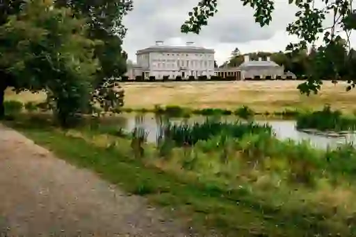View across a pond to Castletown House, a grand Palladian mansion framed by trees and open fields in Kildare.