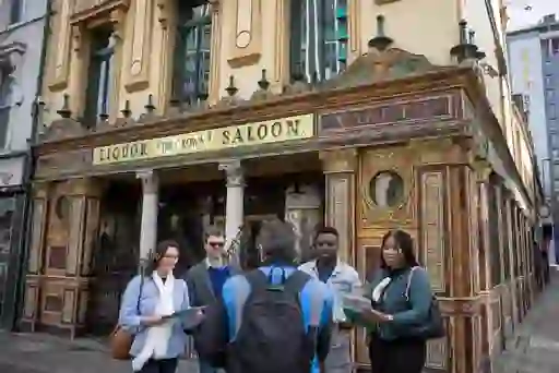 Group of people outside the ornate Victorian façade of the Crown Liquor Saloon in Belfast.