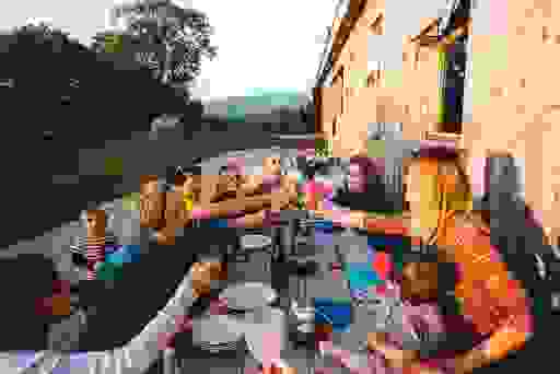 Group of friends sharing an al fresco meal at a rustic wooden table at Rock Farm Slane in County Meath.