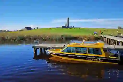 The Erne Water Taxi moored near Devenish Island, with its historic round tower and church ruins visible on the hill.
