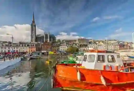 Colourful boats in Cobh Harbour, County Cork, with St Colman’s Cathedral towering over the vibrant waterfront buildings.
