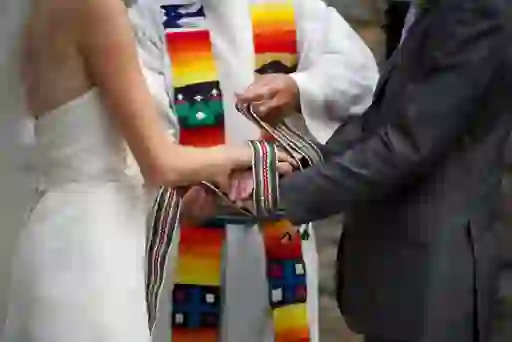 Close-up of handfasting ritual with multicoloured crios binding a couple’s hands during a traditional Irish wedding ceremony.