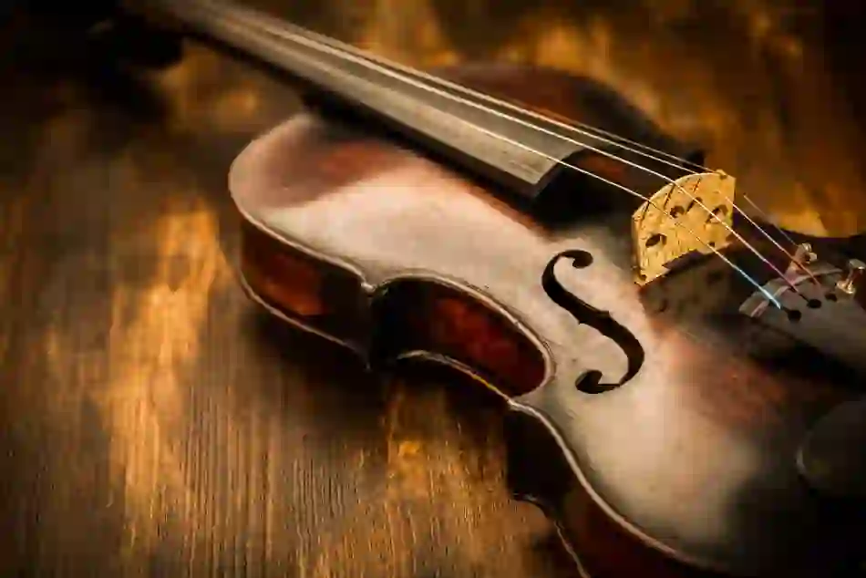 Close-up of a worn Irish fiddle on a wooden table, its golden bridge and warm body lit softly to show fine craftsmanship.