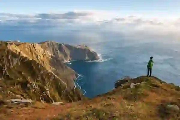Hiker standing at Slieve League cliffs in County Donegal, gazing over the Atlantic Ocean.