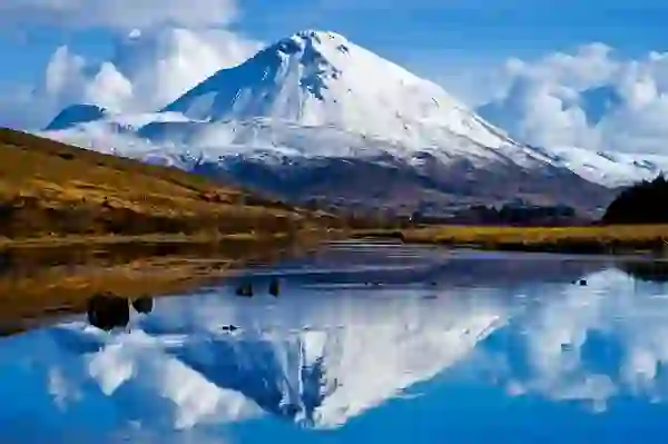 Snow-covered Mount Errigal reflected in still water at its base in County Donegal.