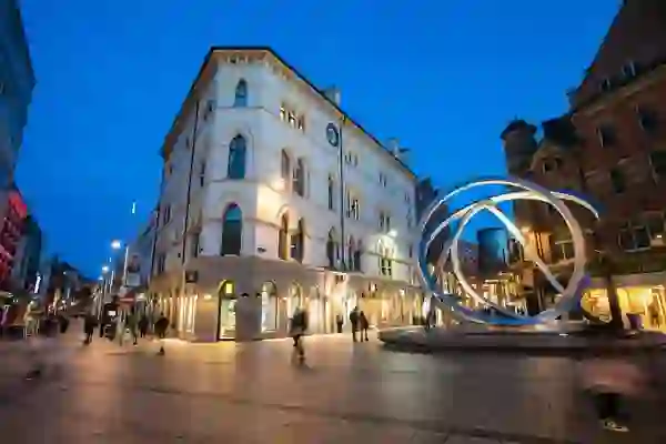 Belfast city centre at dusk with shops, historic buildings and the Spirit of Belfast sculpture.