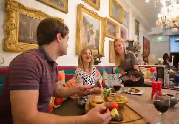 Couple enjoying dinner and wine at the colourful Belfast restaurant, Harlem, with smiling waitress.