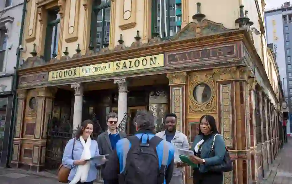 Tour group stands outside the Crown Liquor Saloon’s ornate Victorian tiled facade in Belfast city centre.