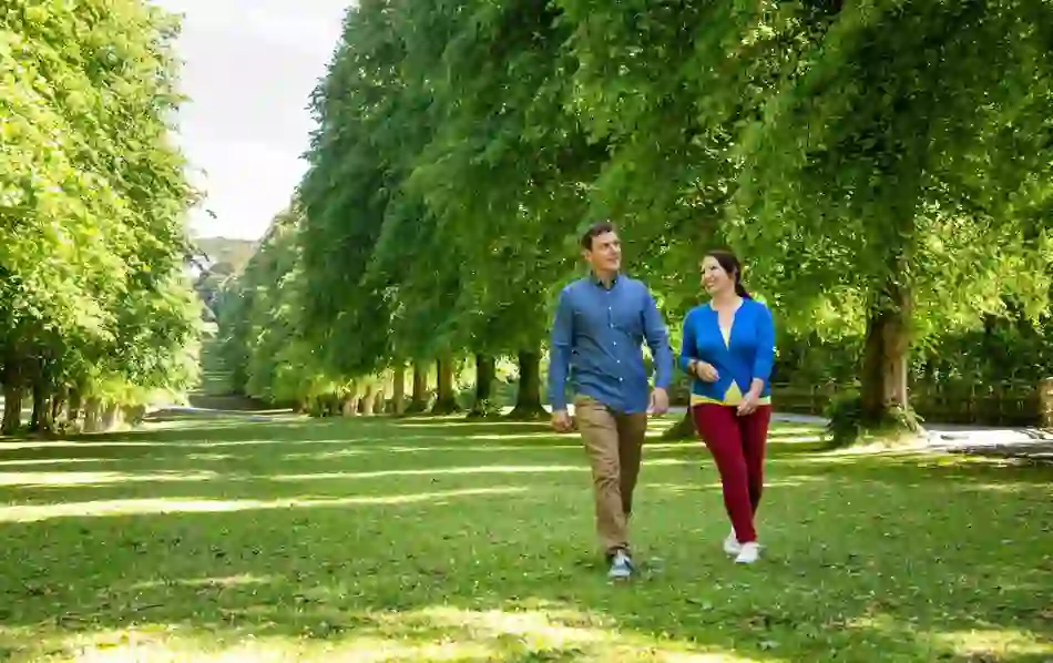 Couple walking under a canopy of trees in Stormont Estate, Belfast.