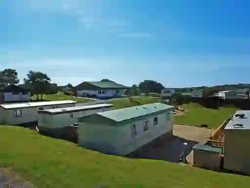 Static mobile homes at a family-friendly holiday park in Ireland, with a play area and clubhouse on a sunny day.