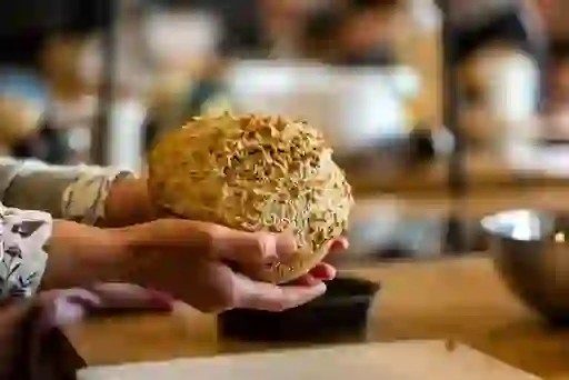 Close-up of fresh Irish brown soda bread held by a baker in a cookery class kitchen.