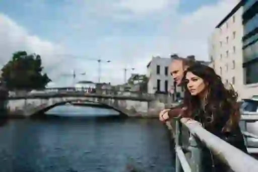 A couple leaning on a railing overlooking a bridge on the River Lee in Cork.