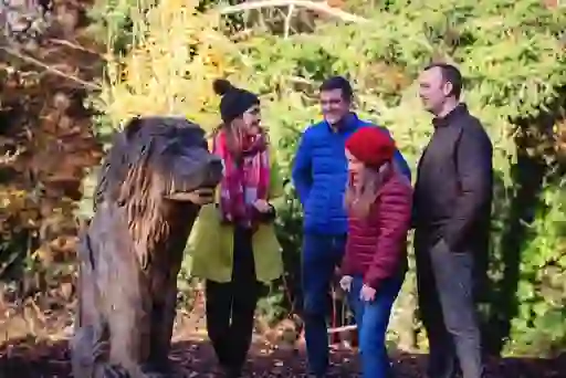 Family gathers around carved lion sculpture on the Narnia Trail in Kilbroney Forest Park, County Down.