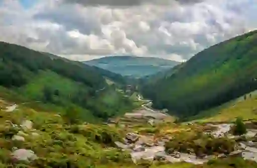 A lush green valley with a winding river running through Glendalough in County Wicklow.