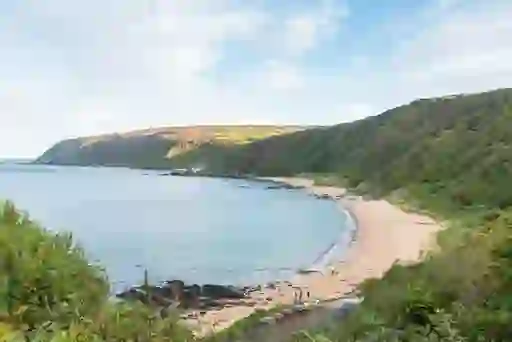 Secluded Kinnagoe Bay on Donegal's Inishowen Peninsula shows a sandy beach curving between cliffs.