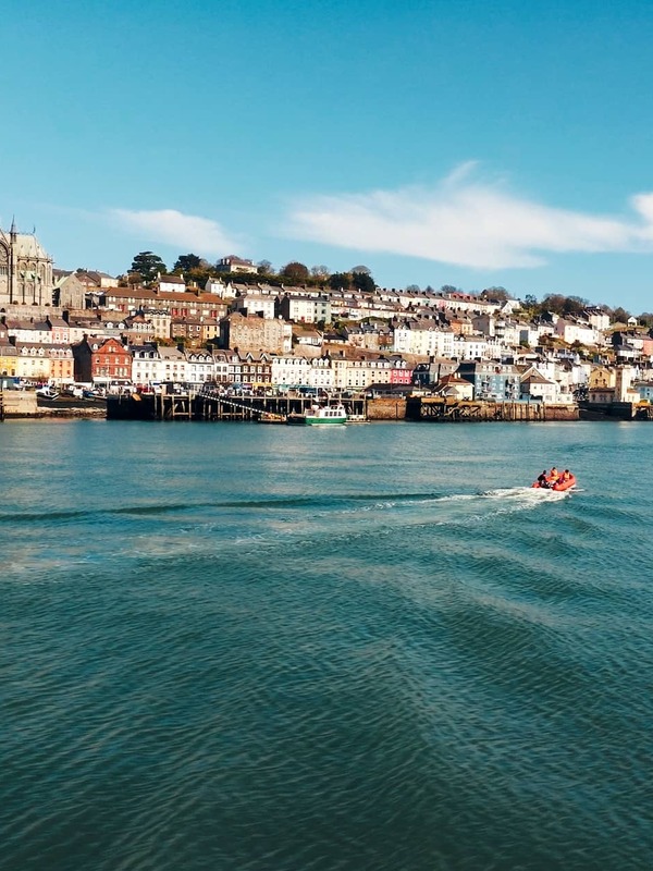 Cobh harbour and St Colman’s Cathedral, County Cork, with colourful waterfront and boat on calm water.