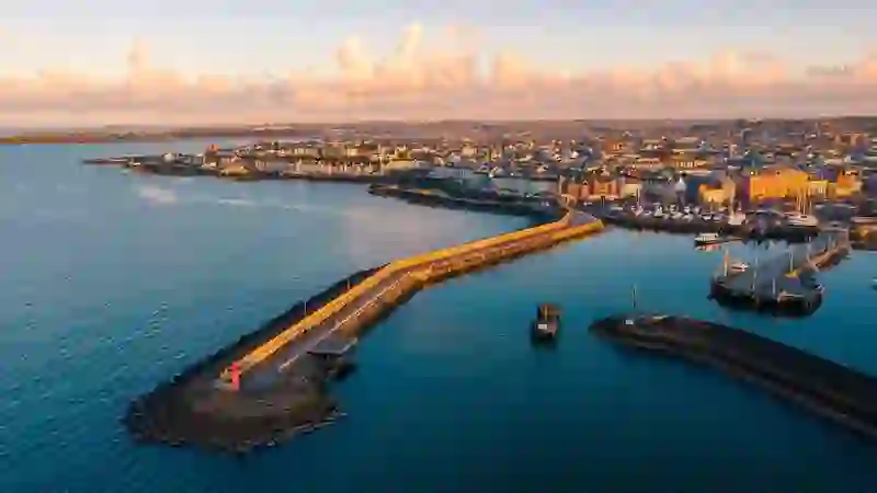 Aerial view of Bangor Harbour in County Down with marina, seafront promenade and calm coastal waters at sunset.