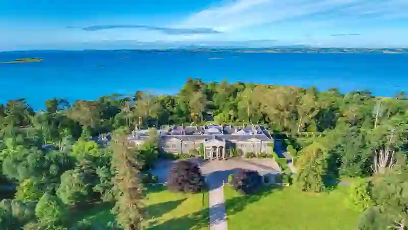 Aerial view of Mount Stewart estate in County Down surrounded by woodland and overlooking Strangford Lough on a sunny day.