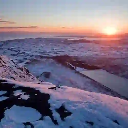 Snow-covered Mourne Mountains at sunrise overlooking rolling countryside, lakes and the coastline near Newry.