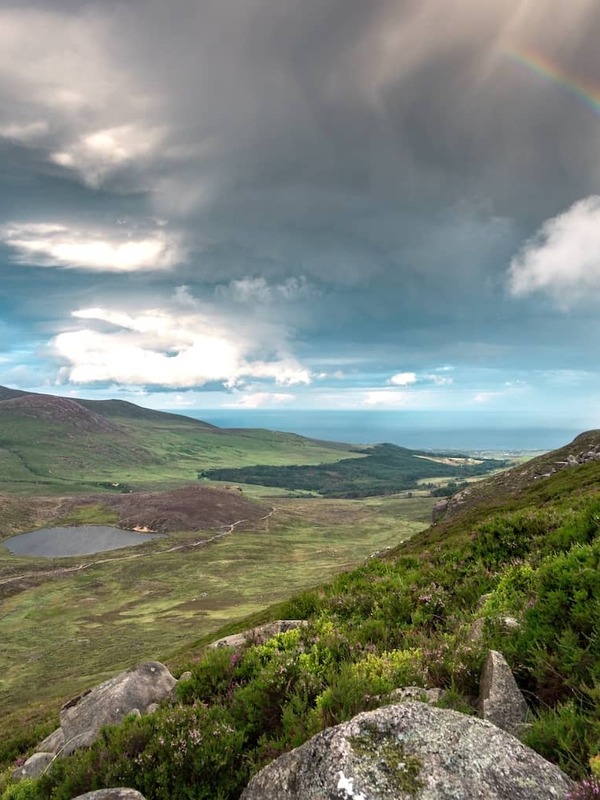 Rainbow over the Mourne Mountains with sweeping valley views, rocky hillsides and dramatic skies in County Down.