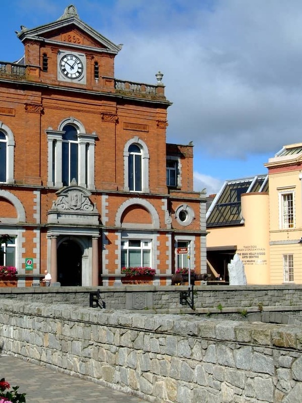 Historic Newry Town Hall beside the canal in County Down with colourful flower displays and blue skies overhead.