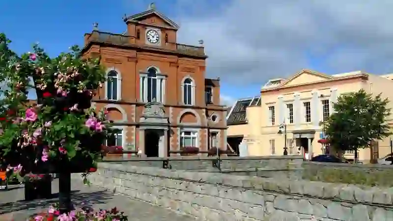 Historic Newry Town Hall beside the canal in County Down with colourful flower displays and blue skies overhead.