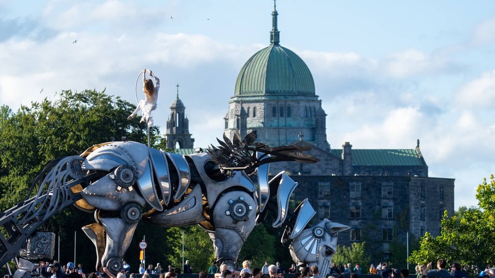 Large mechanical horse parade sculpture performing in Galway city with Galway Cathedral in the background.