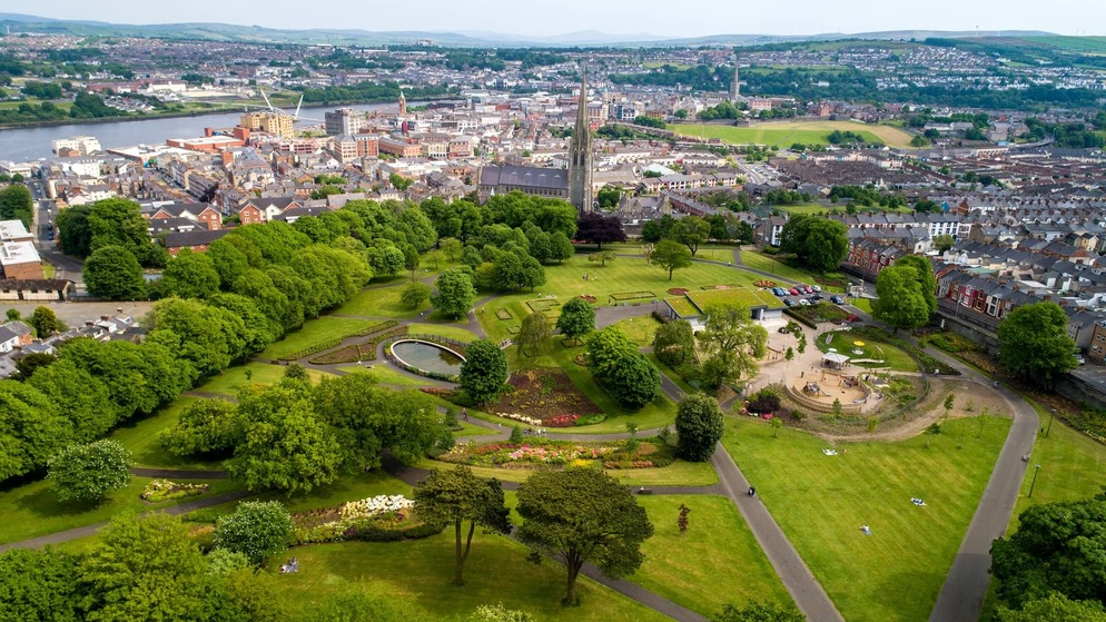 Aerial view of Brooke Park with gardens and Derry~Londonderry city skyline beyond.