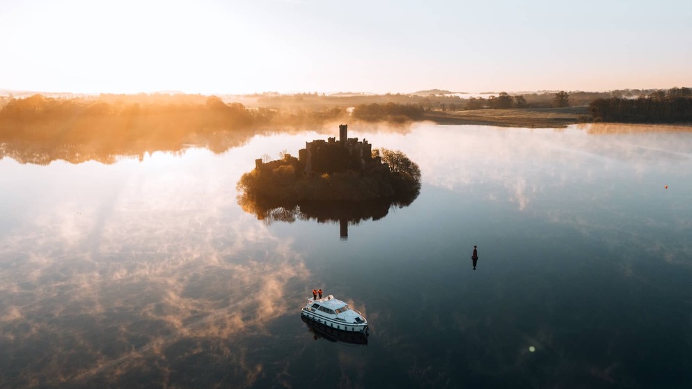Lough Key Forest Park and McDermott’s Castle reflected in calm waters at sunrise, County Roscommon.