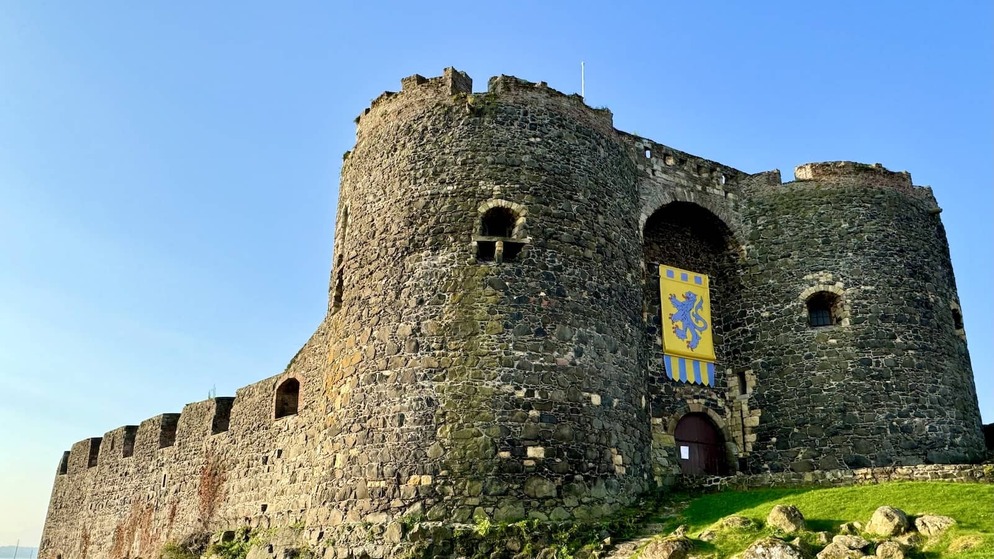 Carrickfergus Castle’s stone towers and battlements under a clear blue sky in County Antrim.