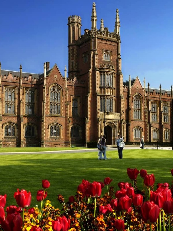 Queen’s University Belfast with red tulips in bloom on the lawn in spring sunshine.