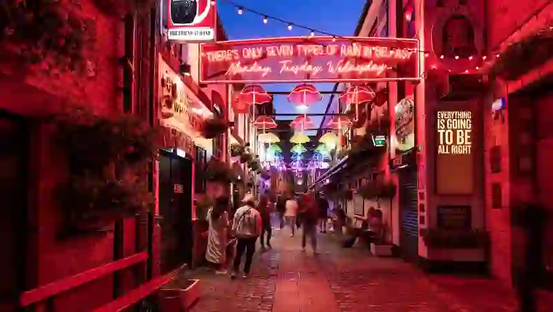 Commercial Court in Belfast at night, glowing with neon signs and colourful umbrella lights overhead.