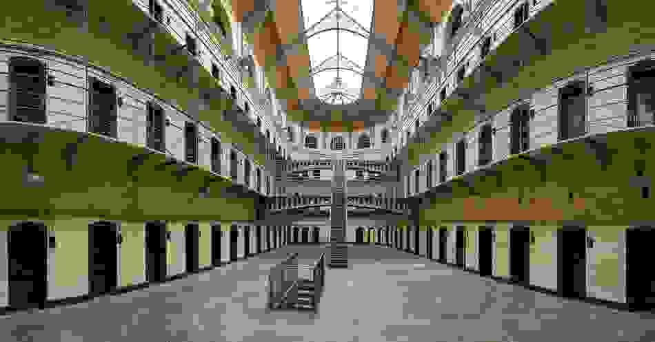Interior of Kilmainham Gaol’s east wing with iron railings, arched ceiling, and historic prison cells.