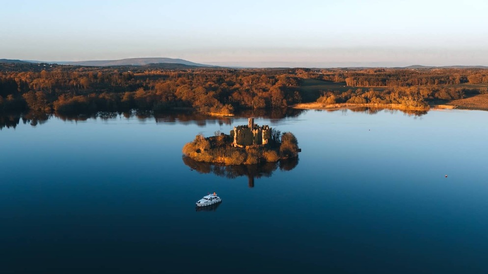 McDermott’s Castle on a small island in Lough Key surrounded by still waters at golden hour, County Roscommon.
