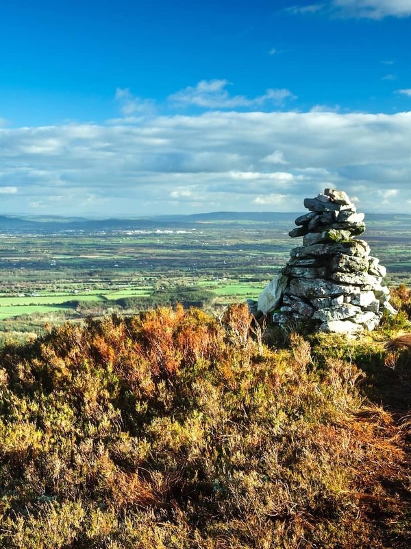 Stone cairn on the Ridge of Capard in the Slieve Bloom Mountains, County Offaly, overlooking a vast landscape of green fields.