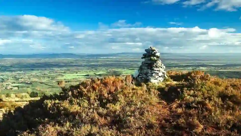 Stone cairn on the Ridge of Capard in the Slieve Bloom Mountains, County Offaly, overlooking a vast landscape of green fields.