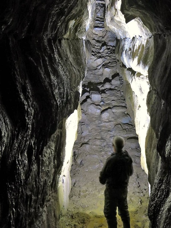 Man stands inside Oweynagat Cave at Rathcroghan in County Roscommon, Ireland, a narrow limestone passage said to lead to the Underworld.