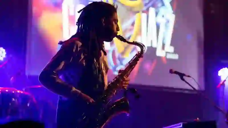 Saxophonist performing on stage under colourful lights at the Cork Jazz Festival.