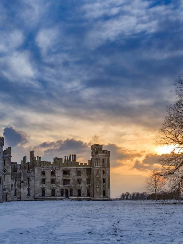 Ducketts Grove in County Carlow at winter sunset, with the gothic ruin set against a dramatic sky and snow-covered grounds.