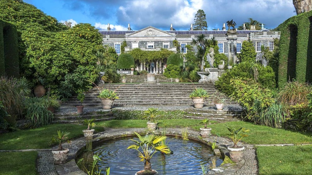 Elegant stone mansion of Mount Stewart framed by lush formal gardens, steps, statues, and a central pond in County Down.