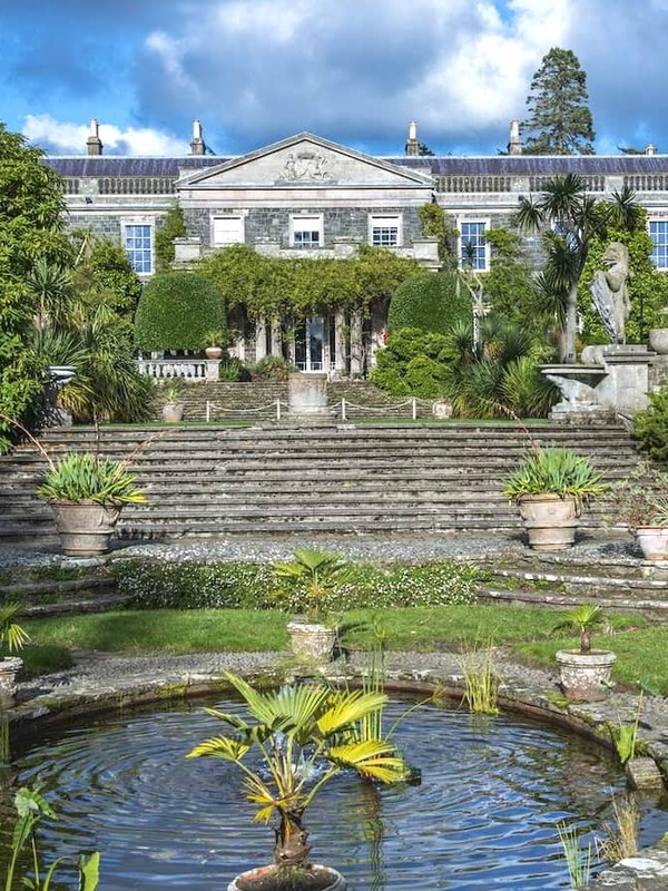 Elegant stone mansion of Mount Stewart framed by lush formal gardens, steps, statues, and a central pond in County Down.