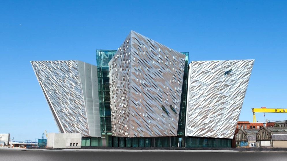 Titanic Belfast’s striking aluminium-clad facade shaped like ship hulls under a clear blue sky in the Titanic Quarter.