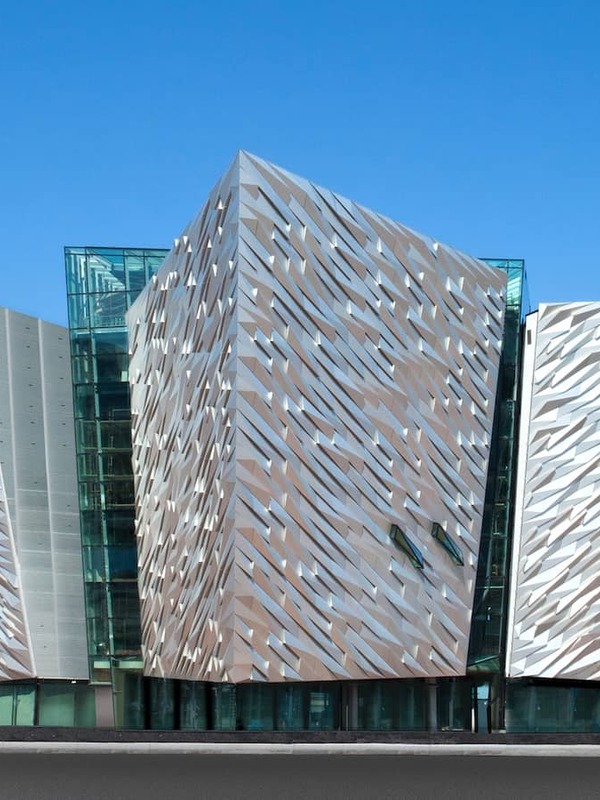 Titanic Belfast’s striking aluminium-clad facade shaped like ship hulls under a clear blue sky in the Titanic Quarter.