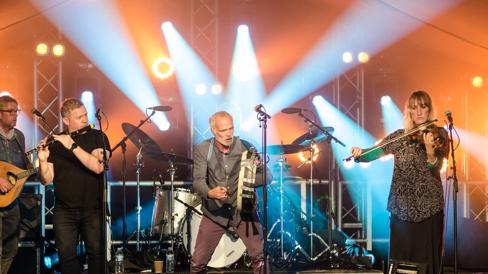 Traditional Irish band performing live under bright stage lights at Cathedral Quarter Arts Festival in Belfast.