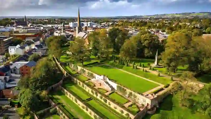 Terraced lawns and formal landscaping of Castle Gardens overlooking Lisburn city in County Antrim under autumn skies.