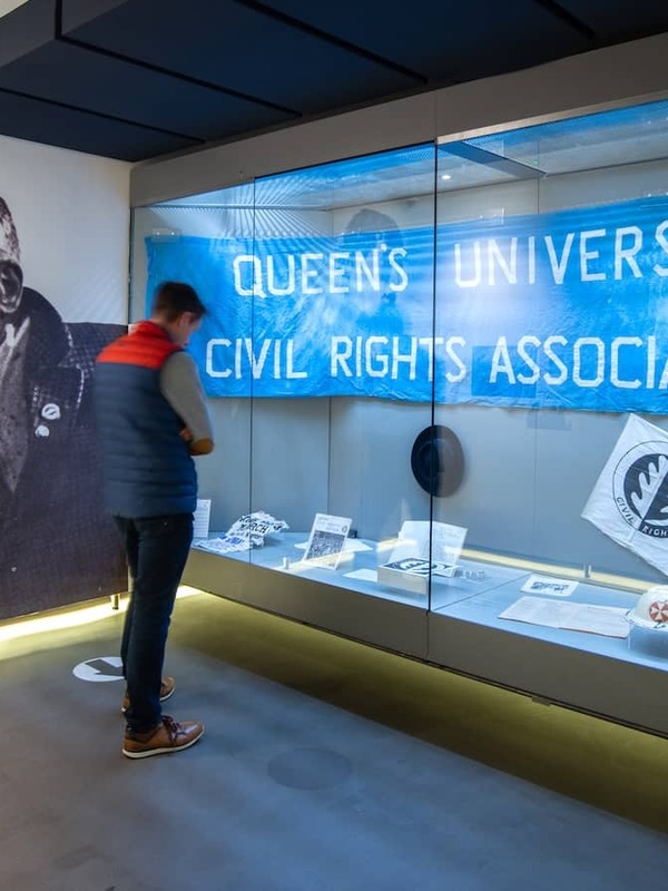 Visitor observing civil rights exhibits at the Museum of Free Derry, with banners and protest memorabilia.