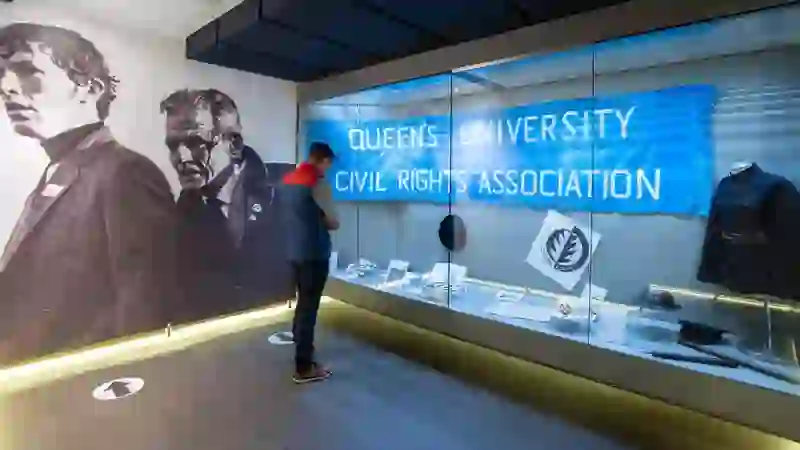 Visitor observing civil rights exhibits at the Museum of Free Derry, with banners and protest memorabilia.