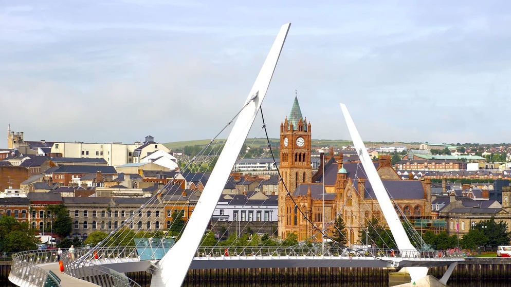 The Peace Bridge curving over the River Foyle with Derry~Londonderry’s Guildhall in the background, Northern Ireland.
