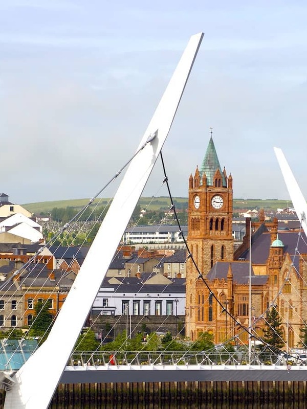The Peace Bridge curving over the River Foyle with Derry~Londonderry’s Guildhall in the background, Northern Ireland.