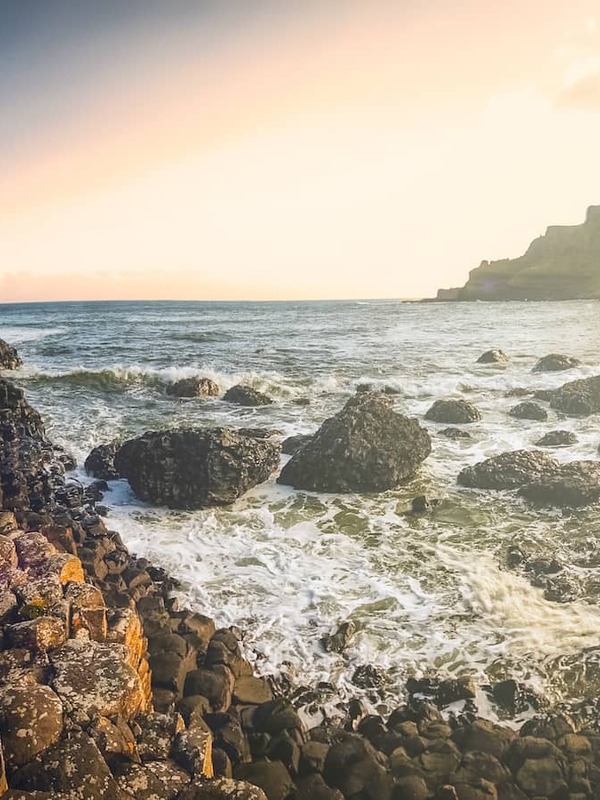 Sunset over the Giant’s Causeway in County Antrim, with hexagonal basalt columns and waves along the rugged coast.